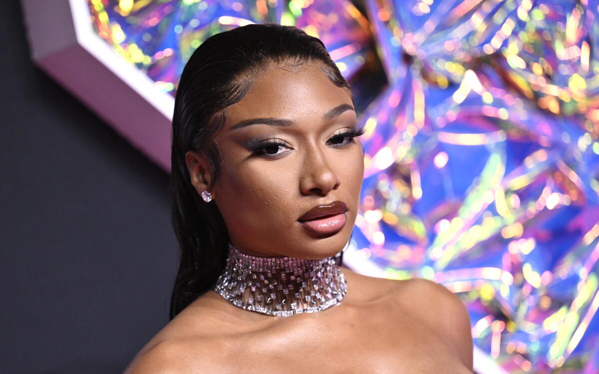 Megan Thee Stallion poses with her hair slicked back, wearing a sparkly choker and diamond stud earrings.