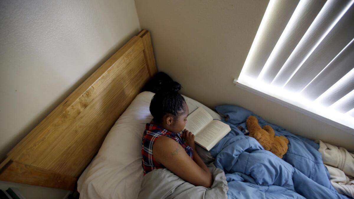 Diamond Hyman, 19, reads in her bed at the David and Margaret Youth and Family Services transitional shelter care facility in La Verne.