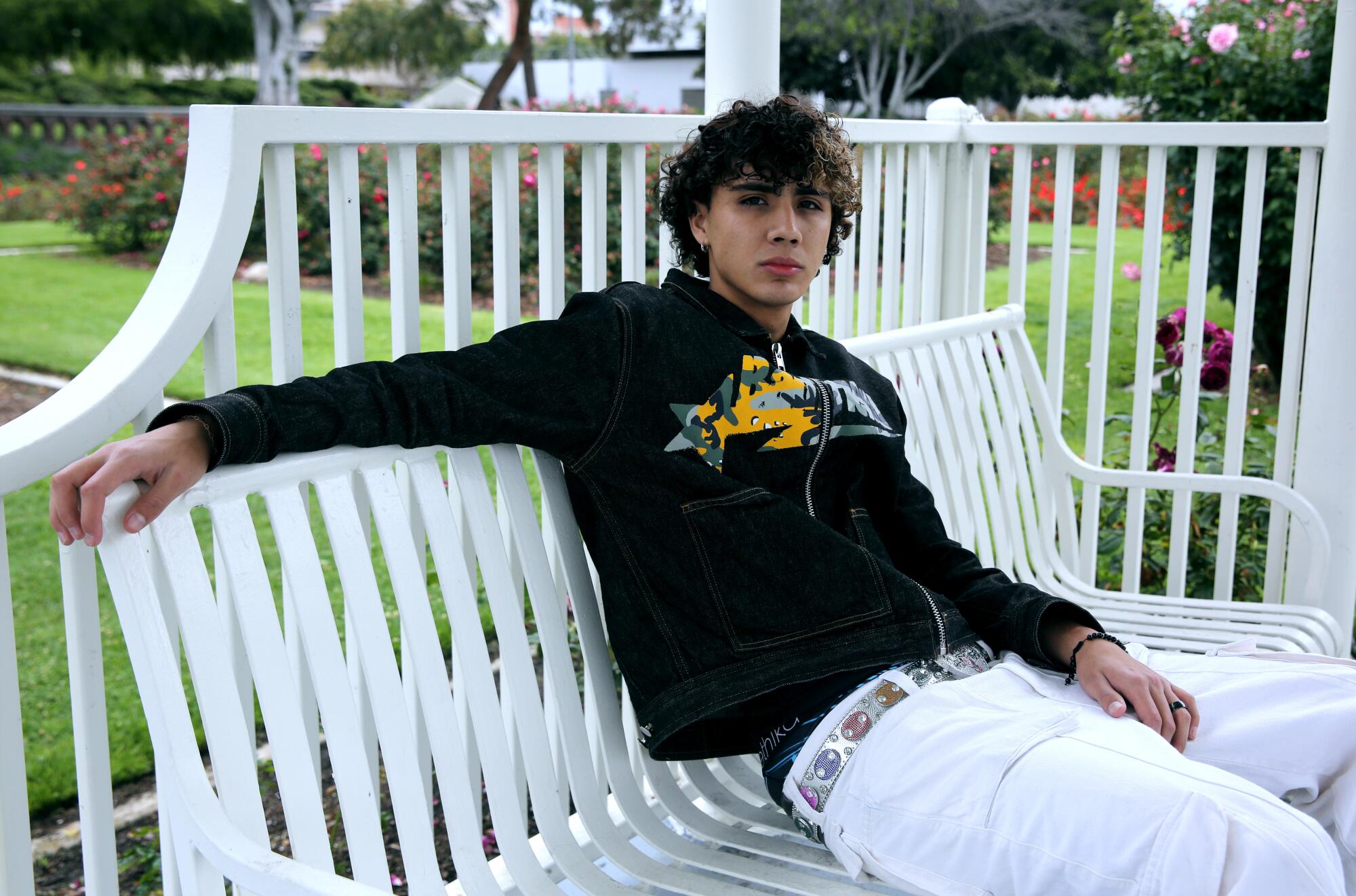 DannyLux sits on a white bench at the Exposition Park Rose Garden