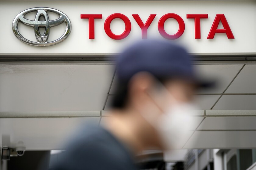 A man walks past a Toyota dealer in Tokyo on May 11, 2022. Toyota Motor Corp. reported Thursday, Aug. 4, 2022 a quarterly profit of 736.8 billion yen ($5.5 billion), down from 897.8 billion yen the previous year. (AP Photo/Eugene Hoshiko)