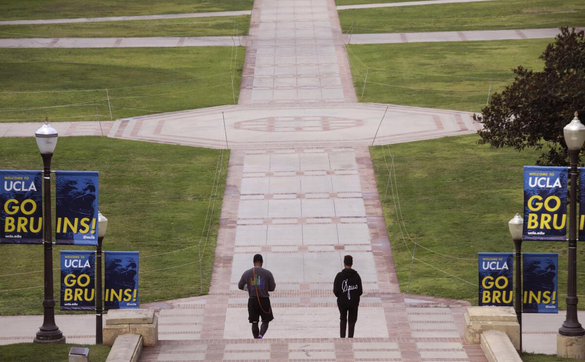 Two people walk down steps on a college campus