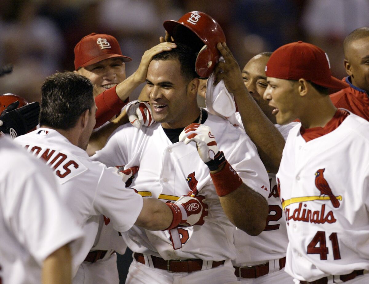 Albert Pujols is mobbed at home plate by his St. Louis Cardinals teammates.