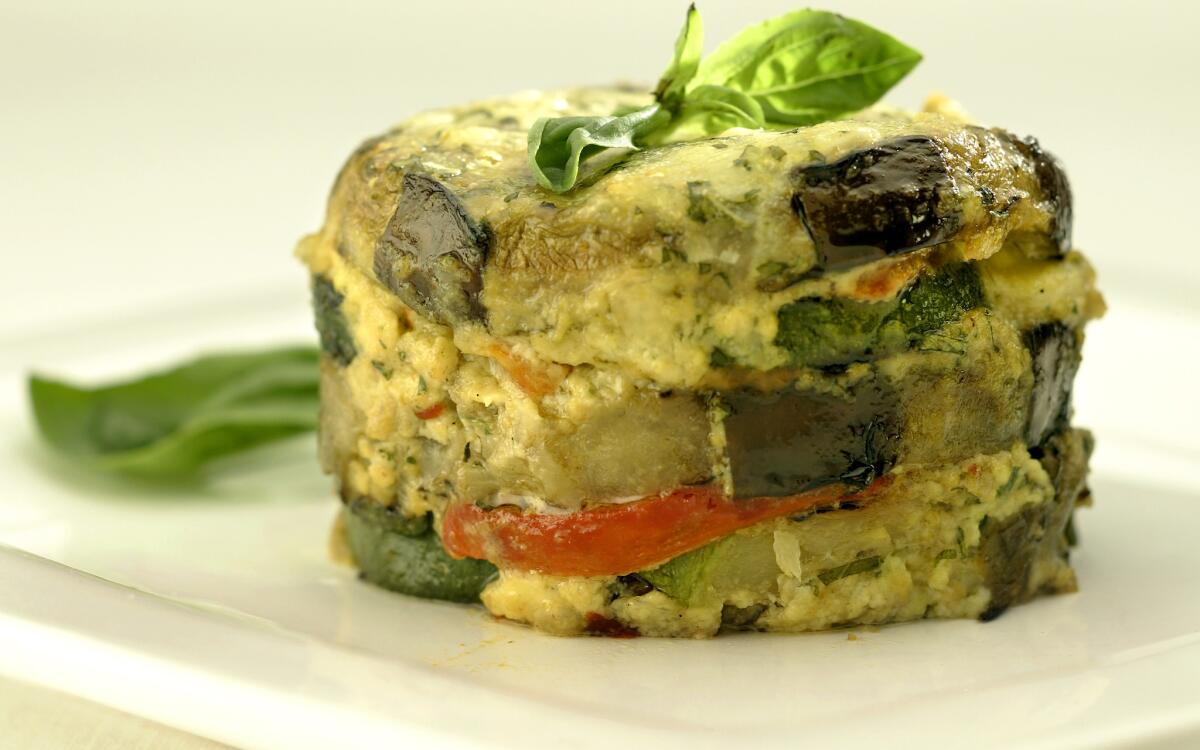 A zucchini-eggplant-pepper timbale garnished with fresh basil leaves