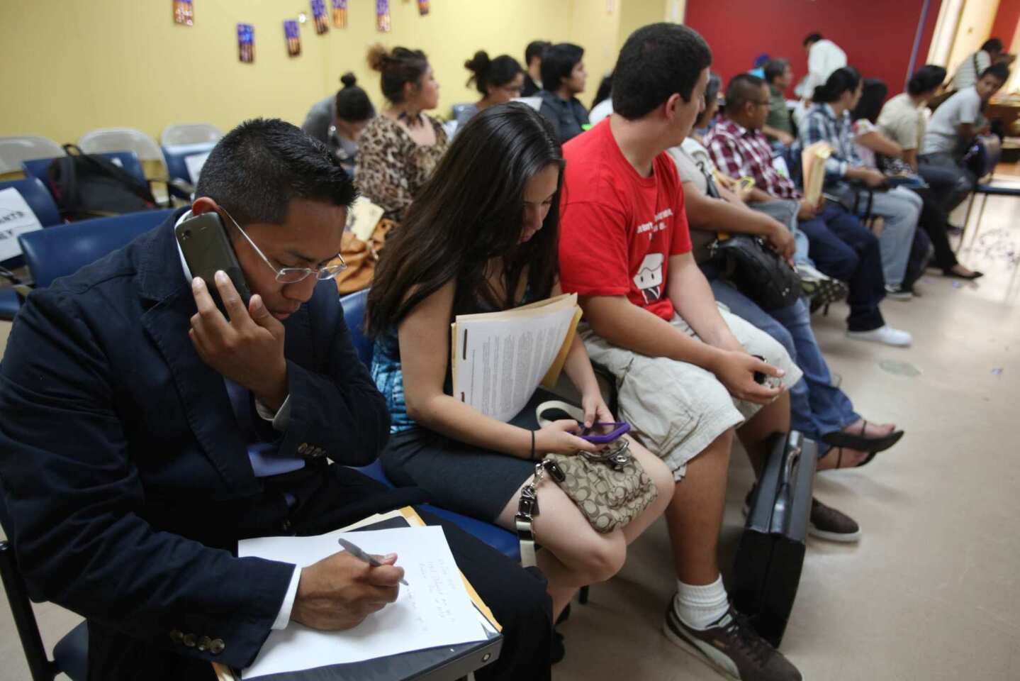 Rigoberto Barboza, left, of La Puente takes notes as he waits to fill out paperwork at the Coalition for Humane Immigrant Rights of Los Angeles. He says he is a attending college and has been in the U.S. since age 11.