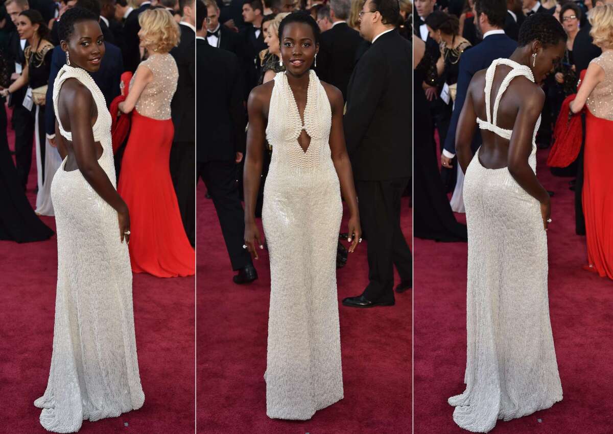 Actress Lupita Nyong'o poses on the red carpet in her Oscars gown by Francisco Costa for Calvin Klein, which was embellished with 6,000 pearls.