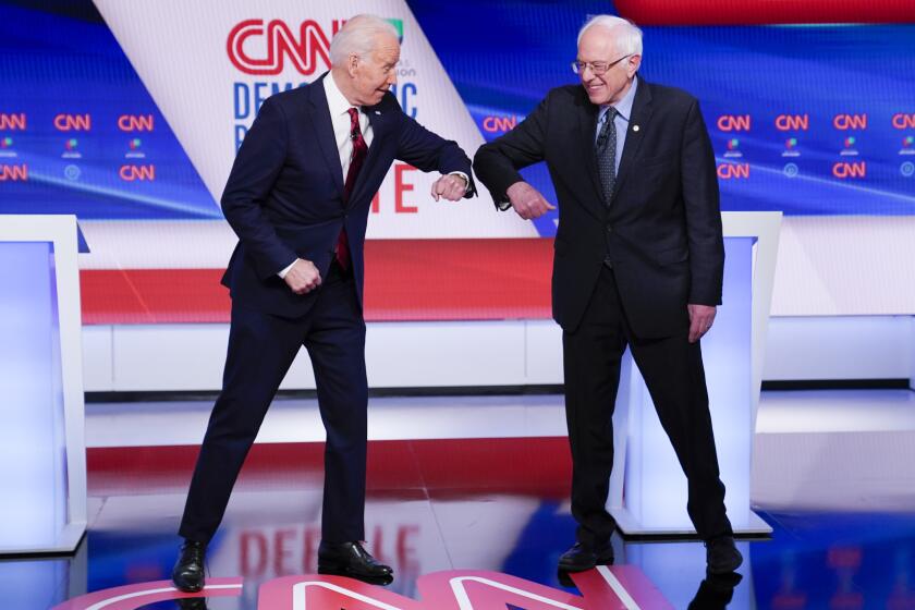 Former Vice President Joe Biden, left, and Sen. Bernie Sanders, I-Vt., right, greet one another before they participate in a Democratic presidential primary debate at CNN Studios in Washington, Sunday.