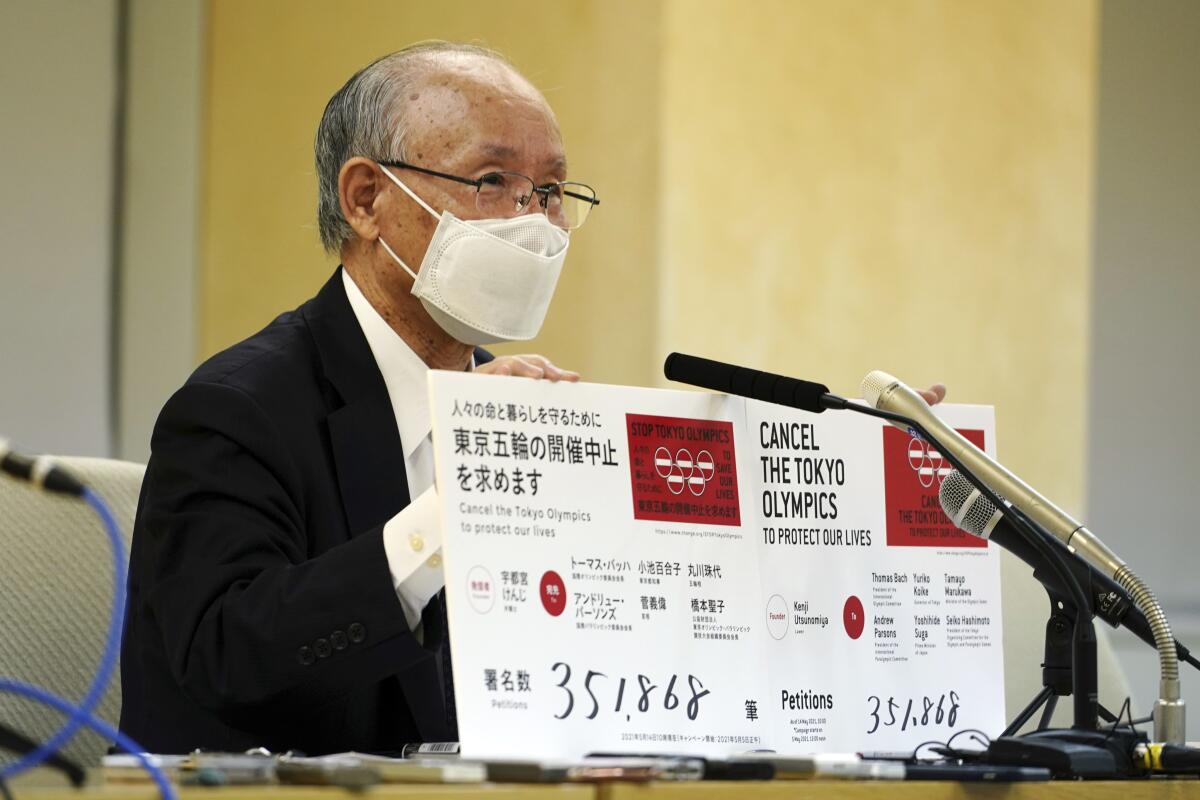 A man holds a "Cancel the Tokyo Olympics" placard.