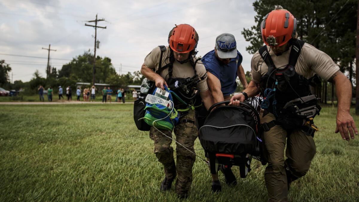 Members of the California Air National Guard 129th Rescue Wing help a man carry his infant with a serious heart condition in Orange, Texas, on Thursday.