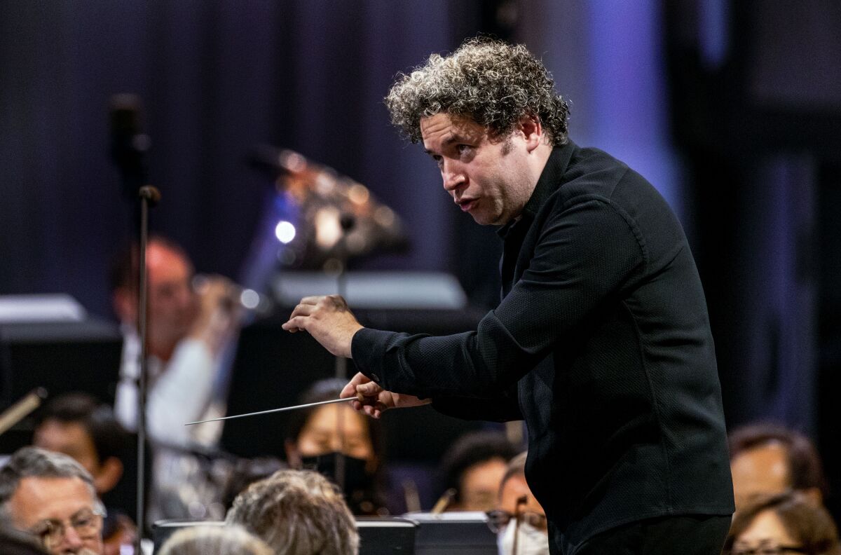 A man in black conducts a philharmonic