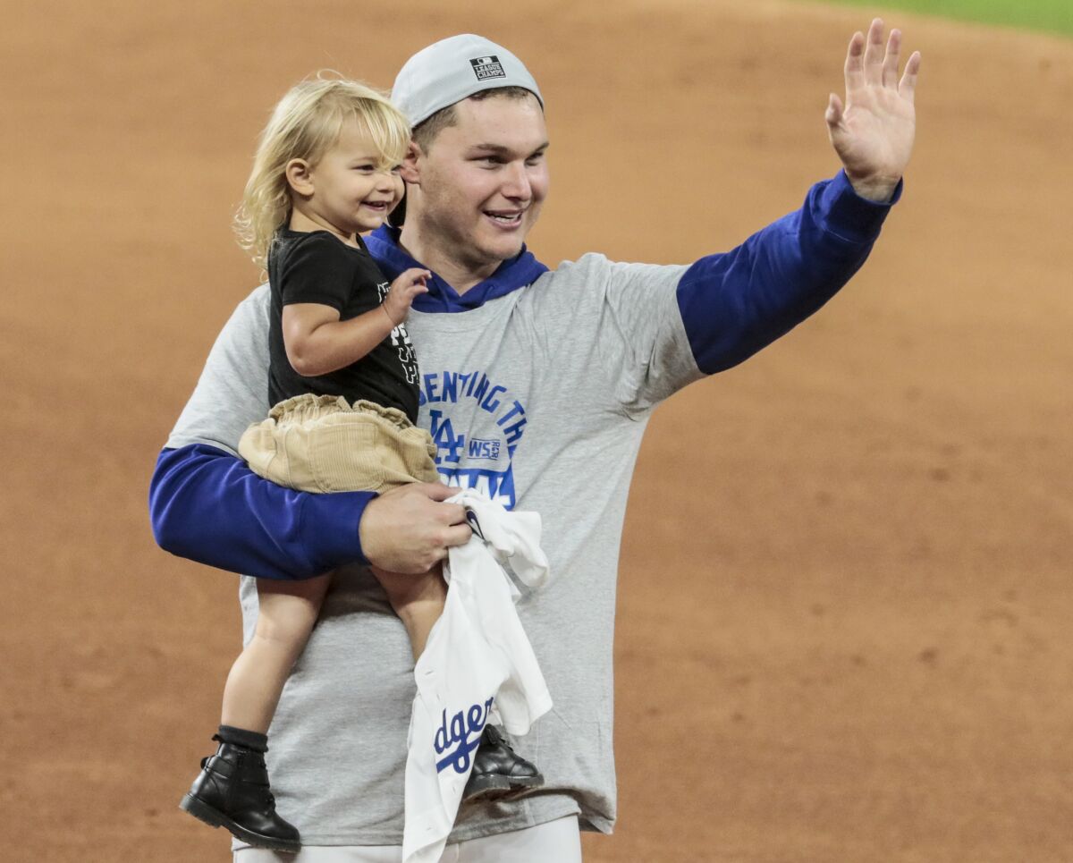 Joc Pederson and his daughter Poppy Jett celebrate on the field after the Dodges beat the Braves 4-3 in Game 7 of the NLCS.