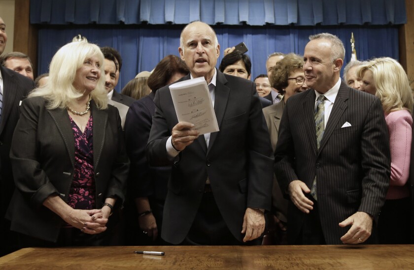 Gov. Jerry Brown, flanked by Assembly Minority Leader Connie Conway, left, and then-Senate President Pro Tem Darrell Steinberg, right, holds up the measure he signed to place a water plan on the November ballot on Aug. 13, 2014.