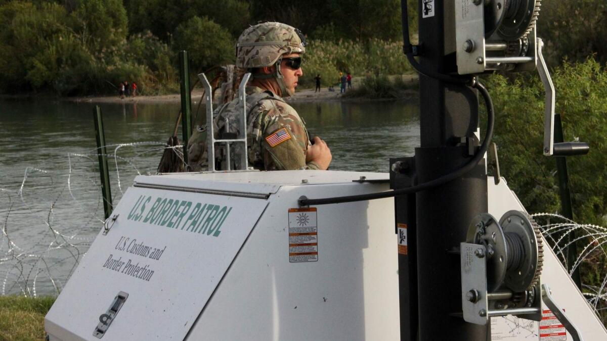 A soldier looks across the Rio Grande from Laredo, Texas, into Nuevo Laredo, Mexico.