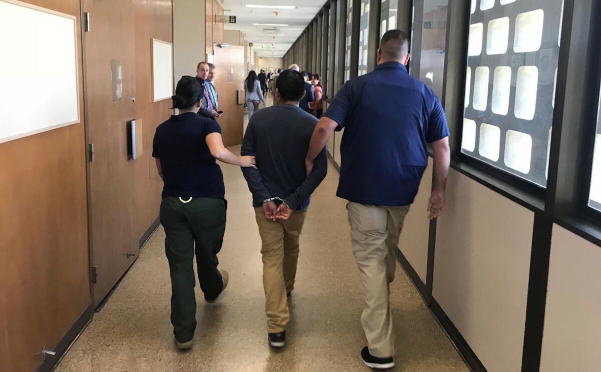 Immigration and Customs Enforcement agents are shown leading a suspect down the hall of Fresno County Superior Court in July 2018. A new California law would prohibit ICE agents from making civil arrests in state courts.