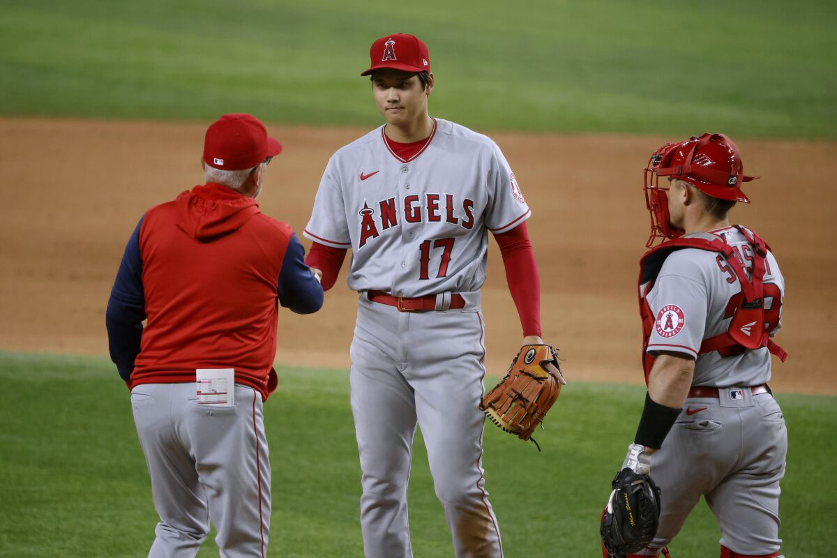 Los Angeles Angels manager Joe Maddon, left, and catcher Max Stassi, right, converge on the mound as starting pitcher Shohei Ohtani (17) is pulled during the fourth inning of the team's baseball game against the Texas Rangers, Thursday, April 14, 2022, in Arlington, Texas. (AP Photo/Michael Ainsworth)