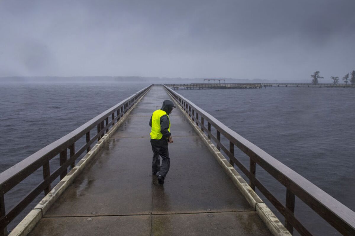 Storm chaser Shaun Piegdon walks down a pier over Louisiana's Lake Arthur on Friday.