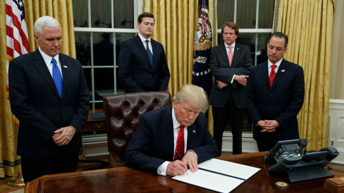 Wrecking crew, Day 1: President Trump, flanked by Vice President Mike Pence and Chief of Staff Reince Priebus, signing an executive order reducing regulations on healthcare in the Oval Office on Friday.
