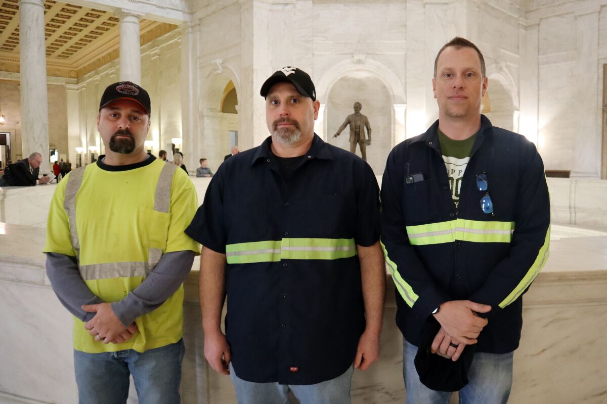 West Virginia coal miners Jason Stewart, Tim Richmond and Cory Lyseski pose for a photo at the West Virginia state Capitol on Tuesday, March 1, 2022 in Charleston, W.Va., while they were visiting to advocate against a bill that would overhaul the state’s mine safety regulation agency and strip the state of its ability to cite coal companies for unsafe working conditions. (AP Photo/Leah M. Willingham)