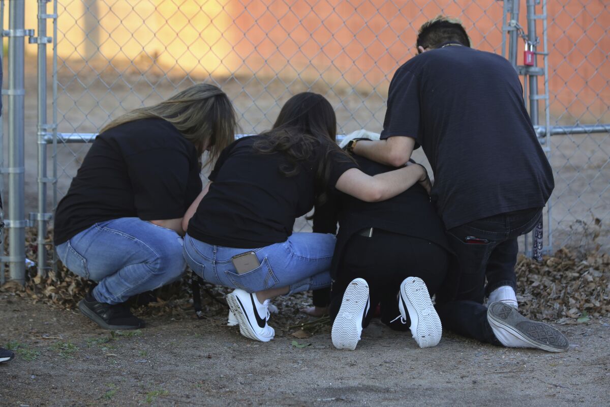 In this March 5, 2020, photo, Antonio Valenzuela's daughters, flanked by friends, kneel, at the spot their father died during an altercation with Las Cruces police on Feb. 29, 2020. An agreement announced Thursday, Aug. 13, 2020, between the city of Las Cruces and a lawyer for Valenzuela's family requires the city to provide racial bias training for police and require officers to intervene in possible excessive force episodes following Valenzuela's choking death. (Bethany Freudenthal/The Las Cruces Sun News via AP)