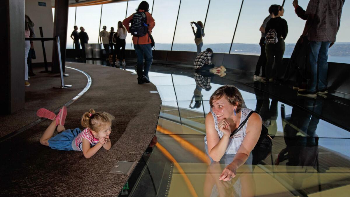 Shauna Bittle lies on the rotating glass floor and tries to convince her daughter Stella Bates, 3, to join her, in the remodeled Space Needle in Seattle.