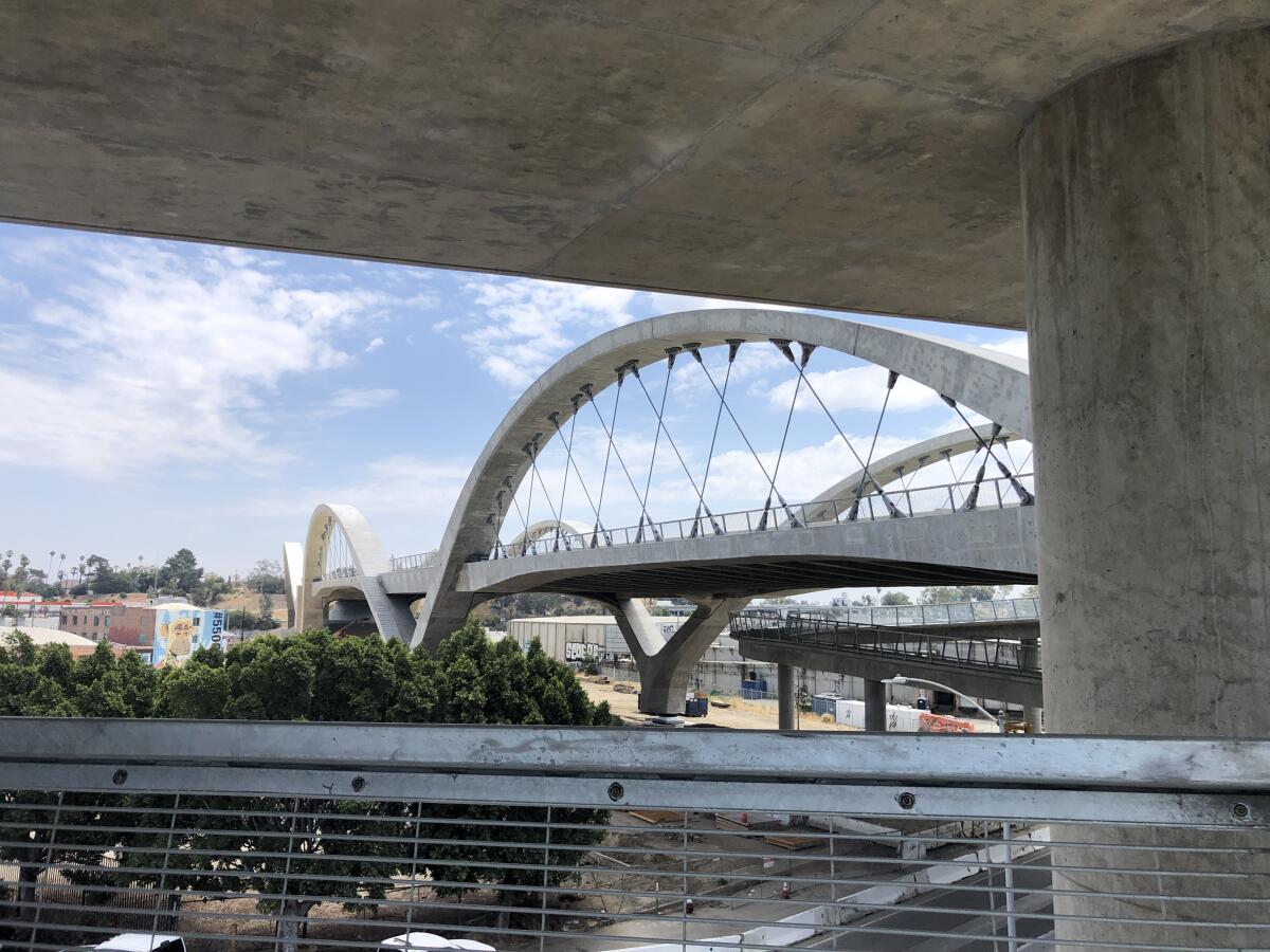 The span of the 6th Street Bridge is framed overhead by the concrete overhang of a spiral ramp.