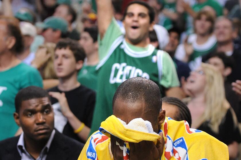 Celtics fans celebrate a playoff win as Kobe Bryant sits on the bench and puts his head in a towel in Boston on June 8, 2008.