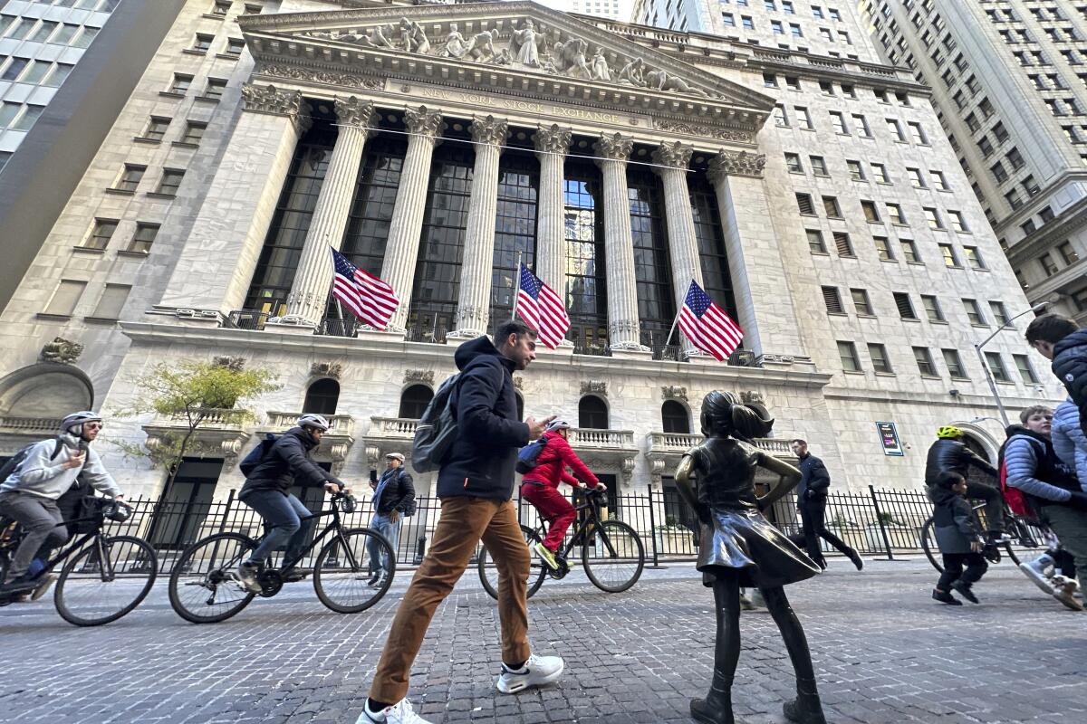 A man passes the "Fearless Girl" statue in front of the New York Stock Exchange