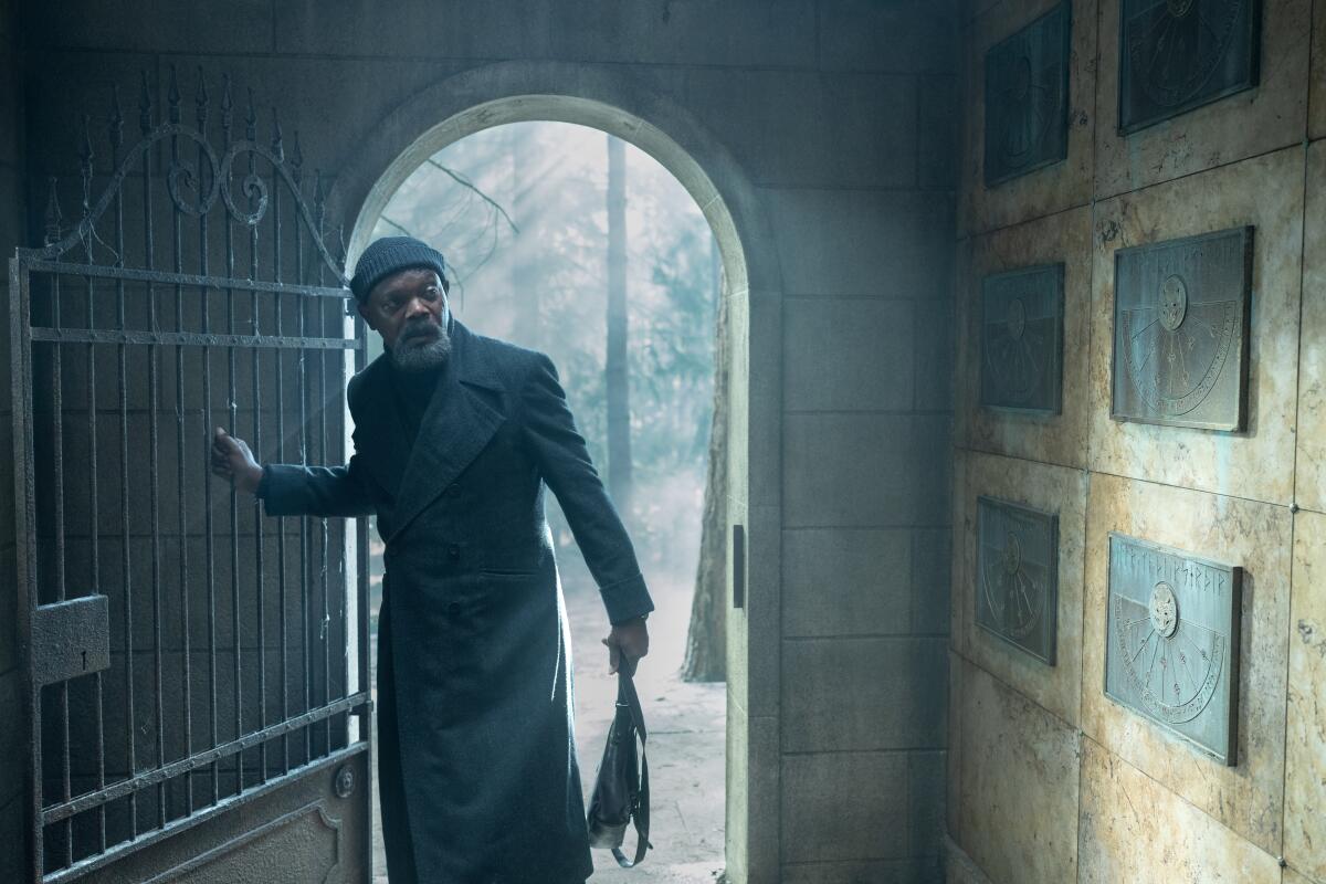 A man walks through the door of a mausoleum.