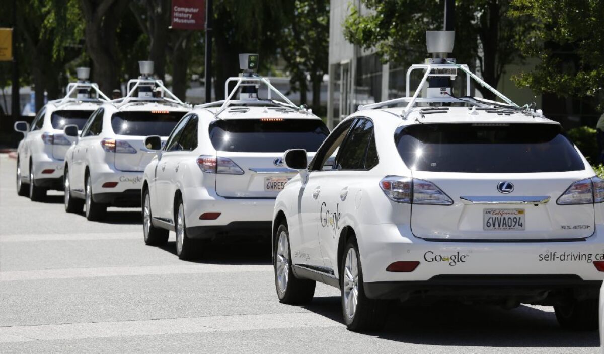 A row of Google self-driving cars sits outside the Computer History Museum in Mountain View. The DMV will miss a year-end deadline to adopt new rules for driverless cars.