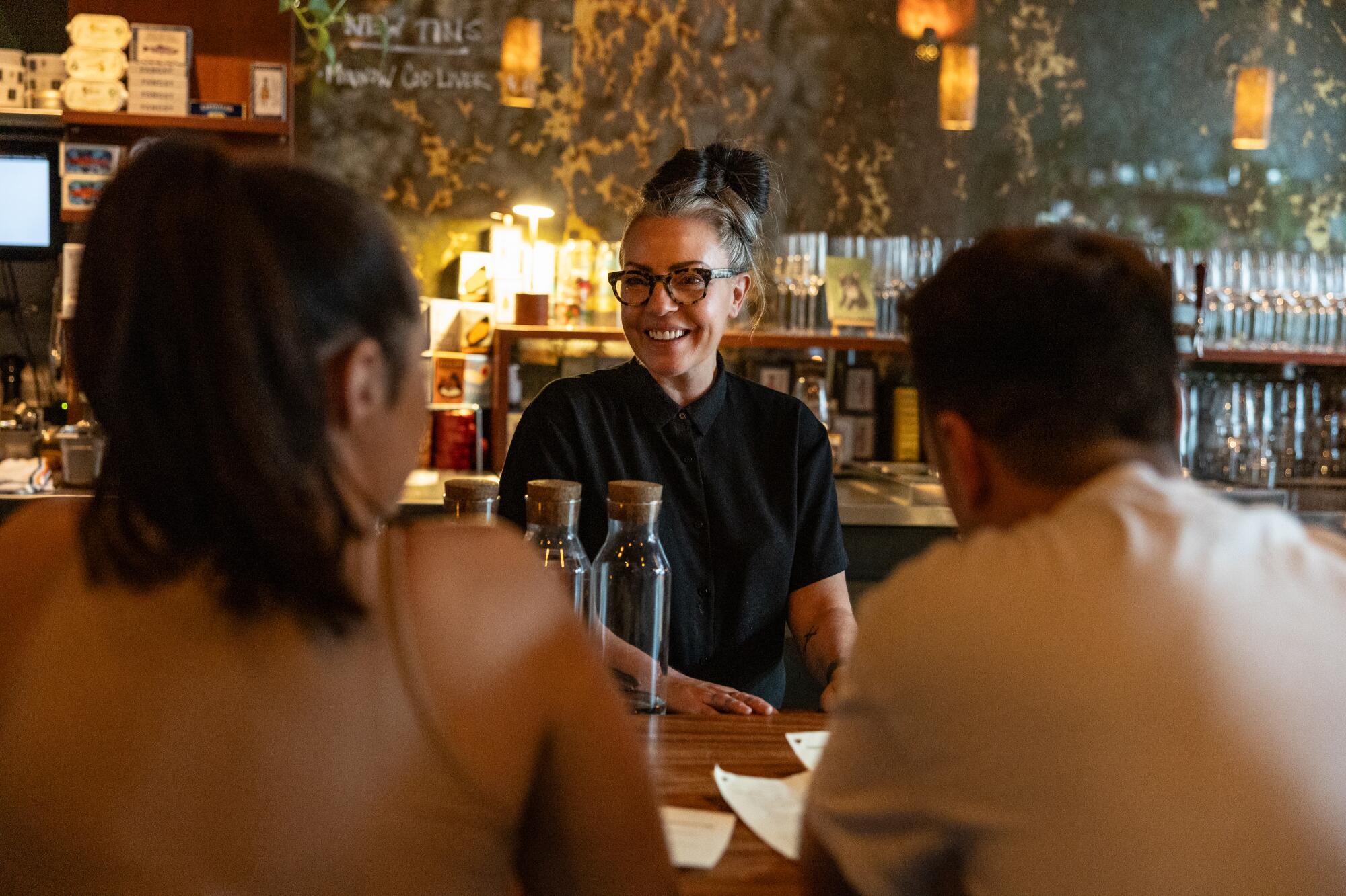 The co -owner of Kippered, Lydia Clarke, talks with customers in her print fish and wines in downtown Los Angeles.