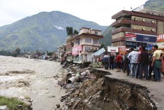 People stand by a road washed away by the River Beas swollen due to heavy rains in Kullu District, Himachal Pradesh, India, Tuesday, July 11, 2023. Heavy monsoon rains caused landslides and flash floods in the country's north, killing at least 15 people over the past few days. (AP Photo/Aqil Khan)