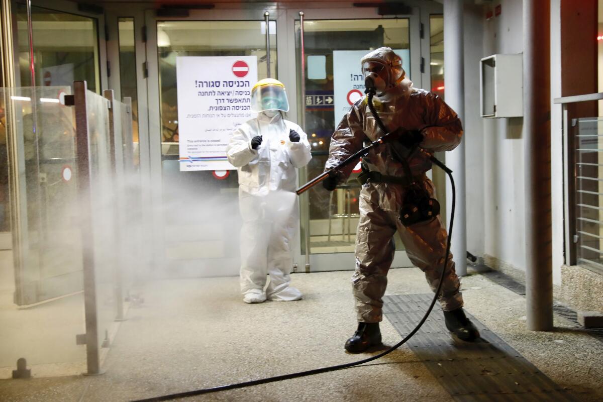 A firefighter sprays disinfectant as a precaution against the coronavirus at the Moshe Dayan Railway Station in Rishon LeTsiyon, Israel, Sunday, March 22, 2020. (AP Photo/Ariel Schalit)
