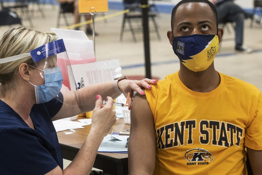 Kent State University student Marz Anderson gets his Johnson & Johnson COVID-19 vaccination from Kent State nurse Beth Krul in Kent, Ohio, Thursday, April 8, 2021. U.S. colleges hoping for a return to normalcy next fall are weighing how far they should go in urging students to get the COVID-19 vaccine, including whether they should — or legally can — require it. (AP Photo/Phil Long)