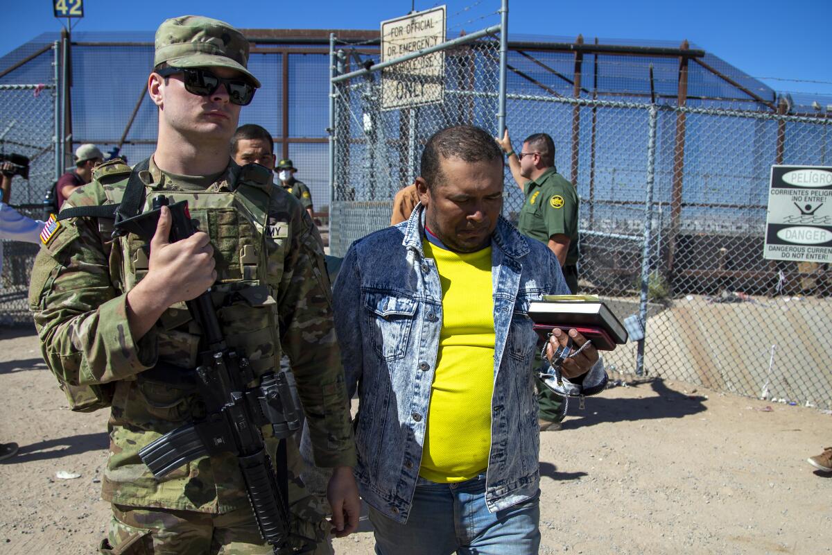 Migrants are escorted by a U.S. Army soldier after entering into El Paso from Juarez, Mexico