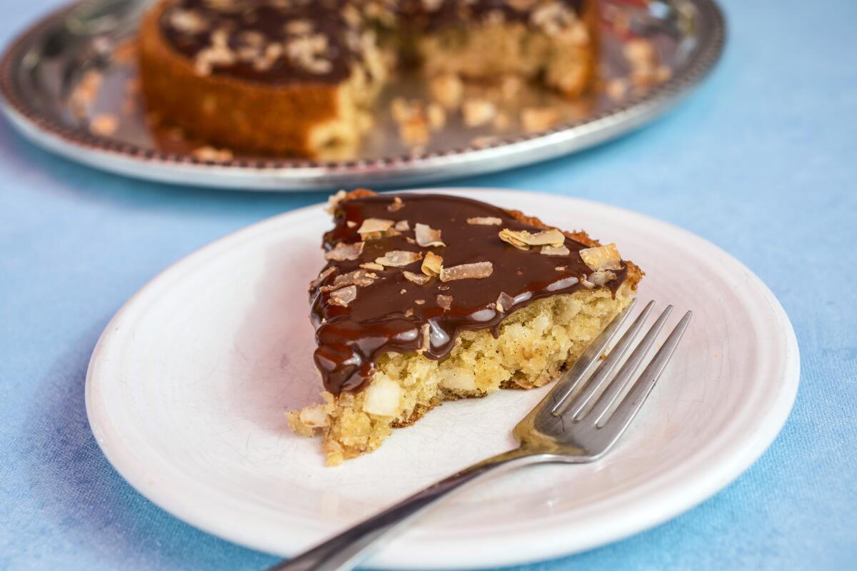 A slice of chewy coconut cake with milk chocolate glaze on a plate with a fork.