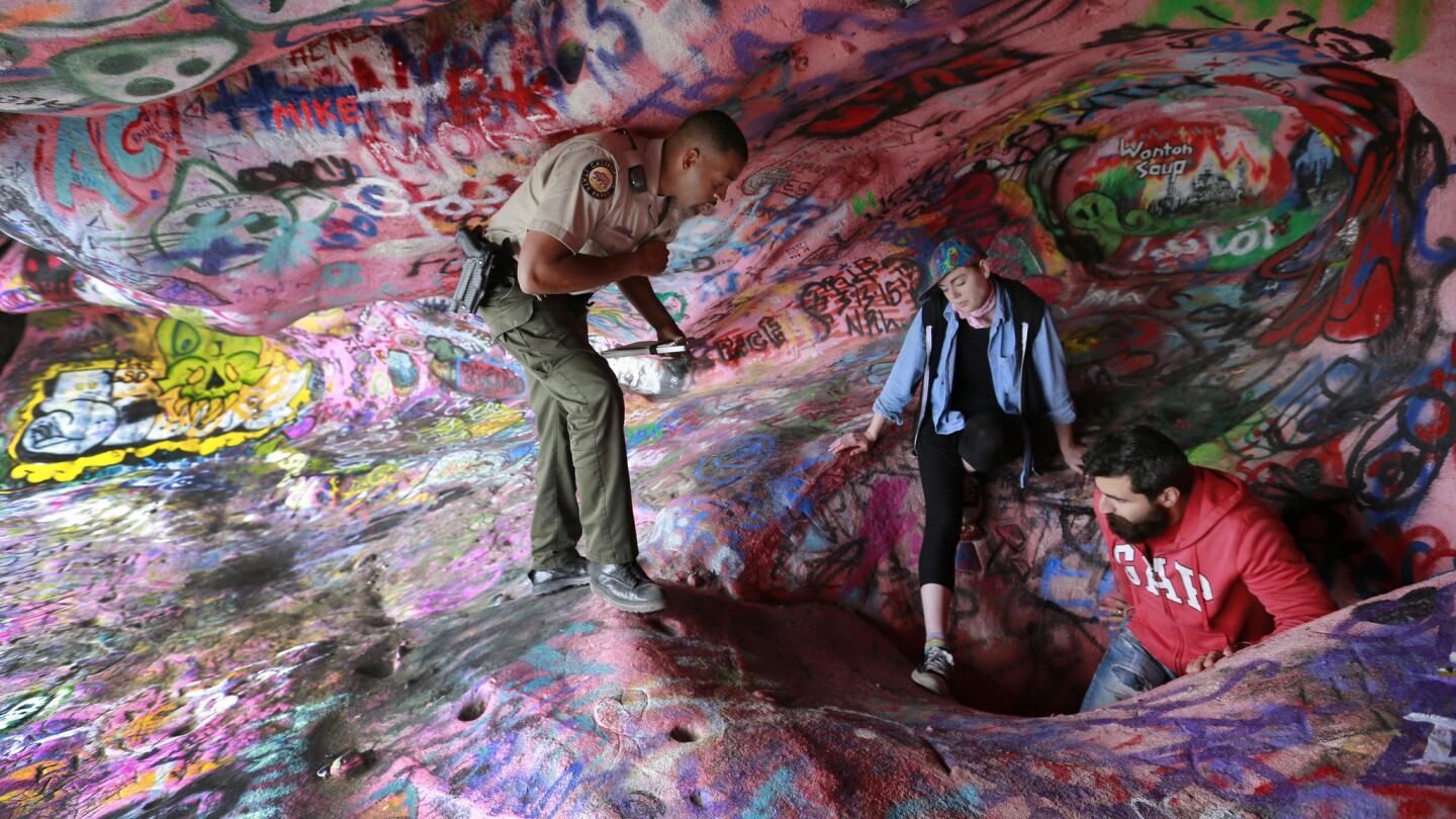 California State Park ranger Dexter Crowder watches trespassing artists leave Corral Canyon Cave after he issued a citation. The cave is better known by the misleading moniker, Jim Morrison Cave. It was closed to the public until further notice. Large crowds have shown up on a daily basis to see the vandalized cave and in some cases add to the vandalism with graffiti of their own.
