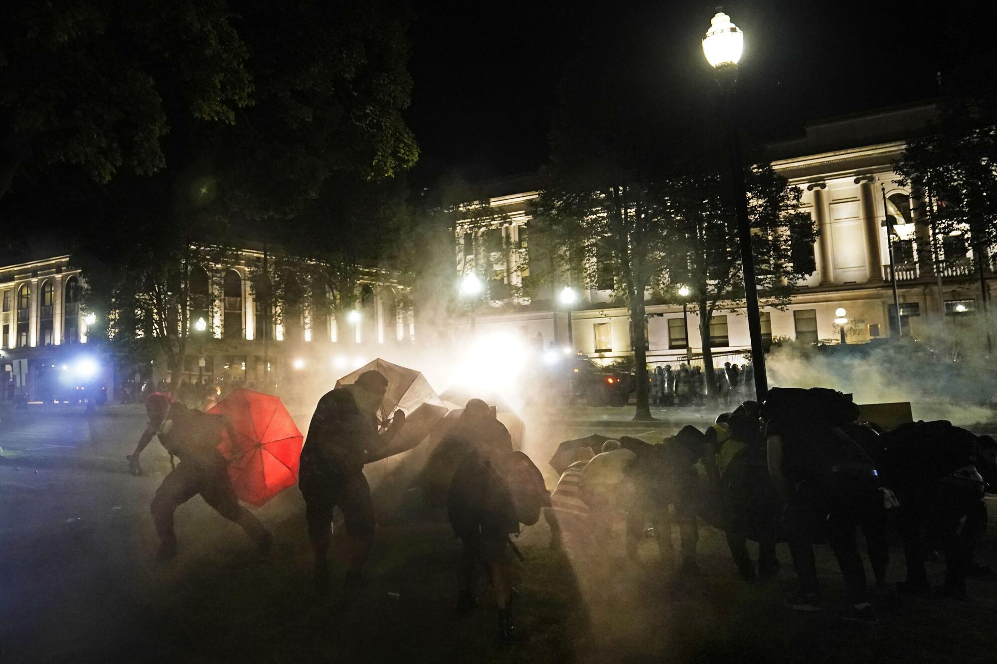 Protesters take cover from tear gas fired by police.