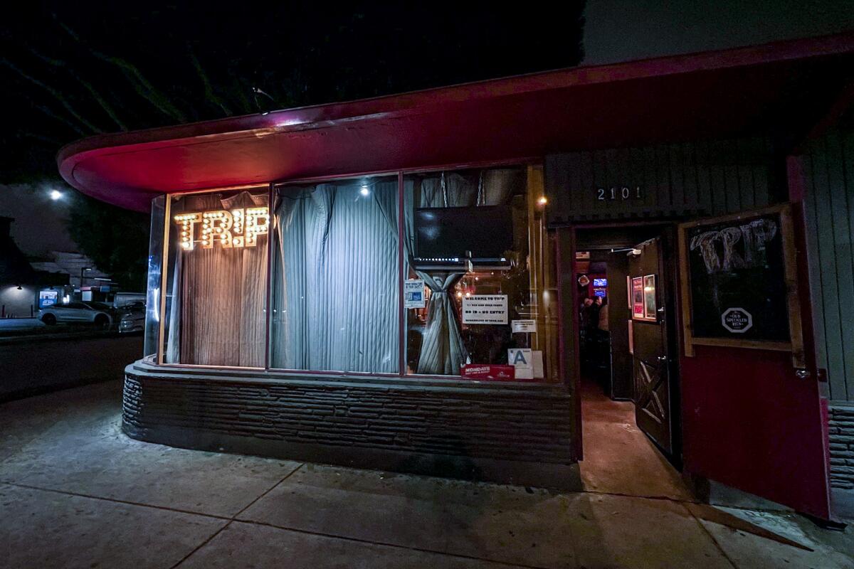 The nighttime facade of a bar with the word "Trip" in lights