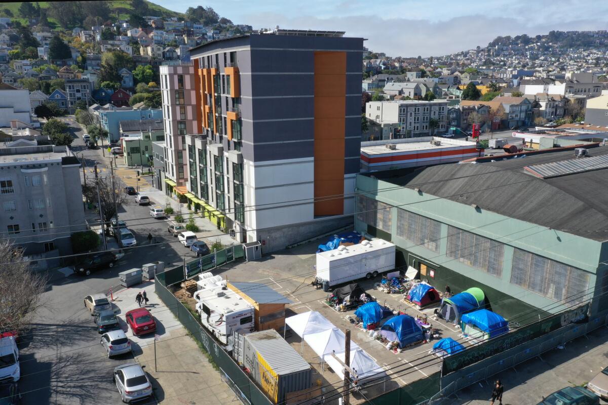 A grouping of tents near a multistory building in San Fransicso.