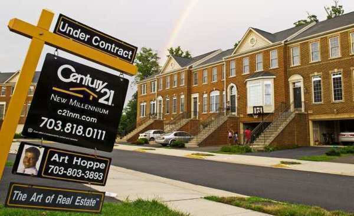 A rainbow is seen in the distance behind a real estate sign in a community of town homes in Centreville, Va.