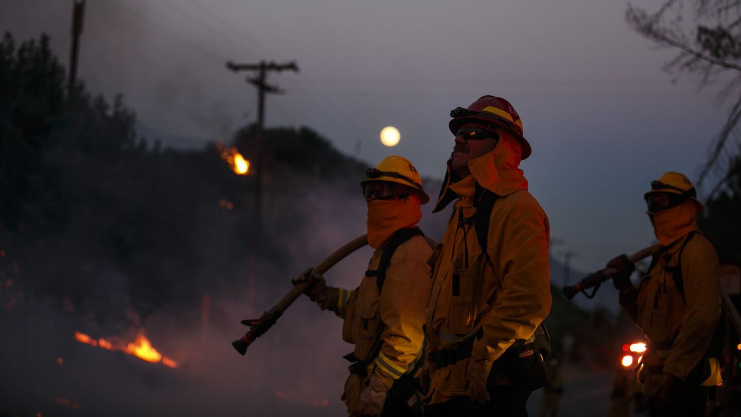 With a full moon in the background, firefighters monitor the Blue Cut fire along Lytle Creek Road on Wednesday night.
