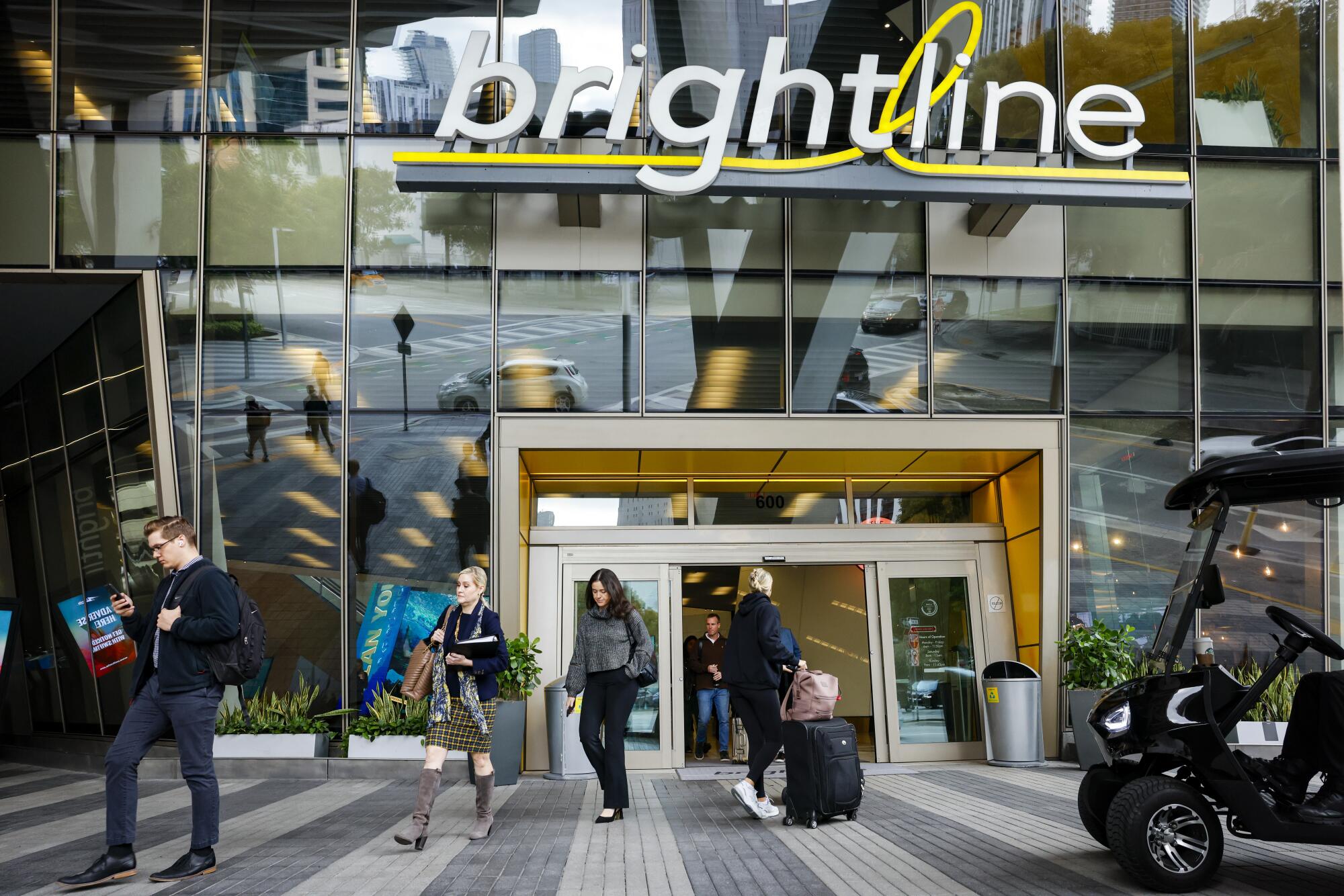 A glass-fronted entrance with the sign "brightline" and people walking outside