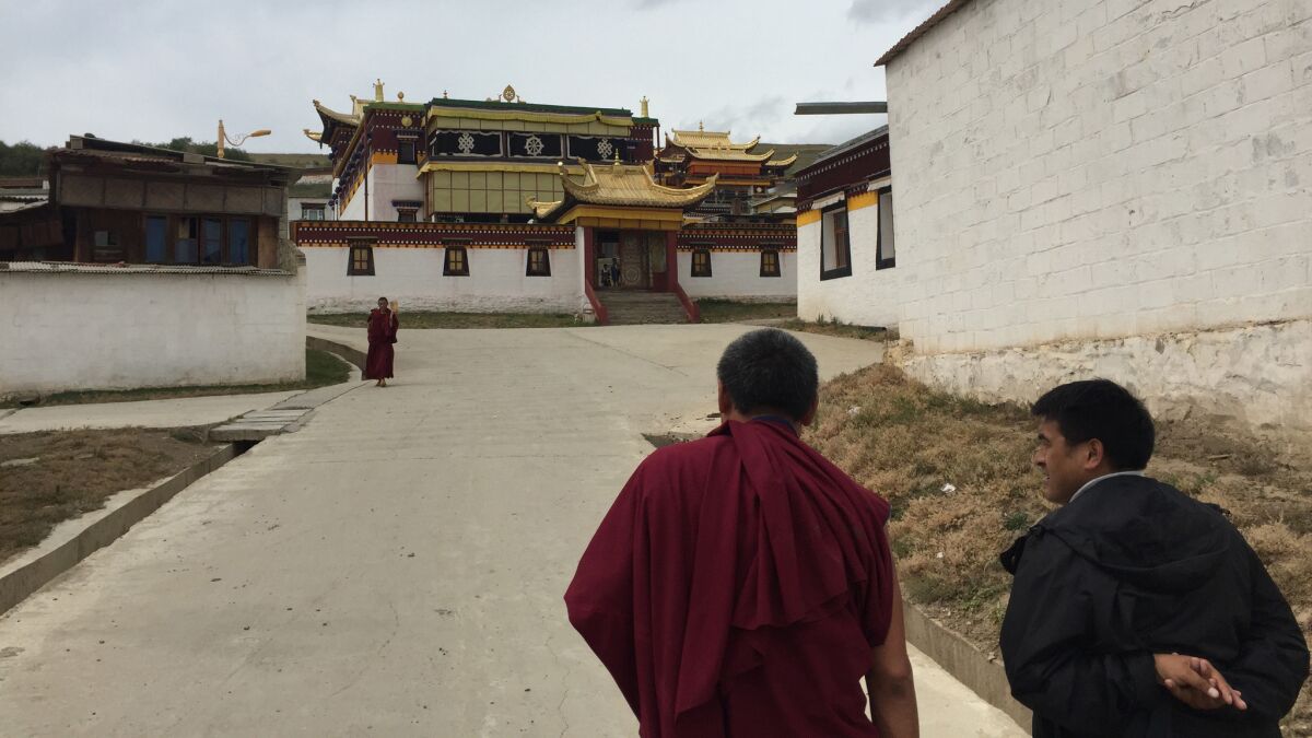 A monk and an official at the Dazha Monastery in Ruoergai County, Aba prefecture, chat as they walk toward a prayer room. (Jonathan Kaiman / Los Angeles Times)