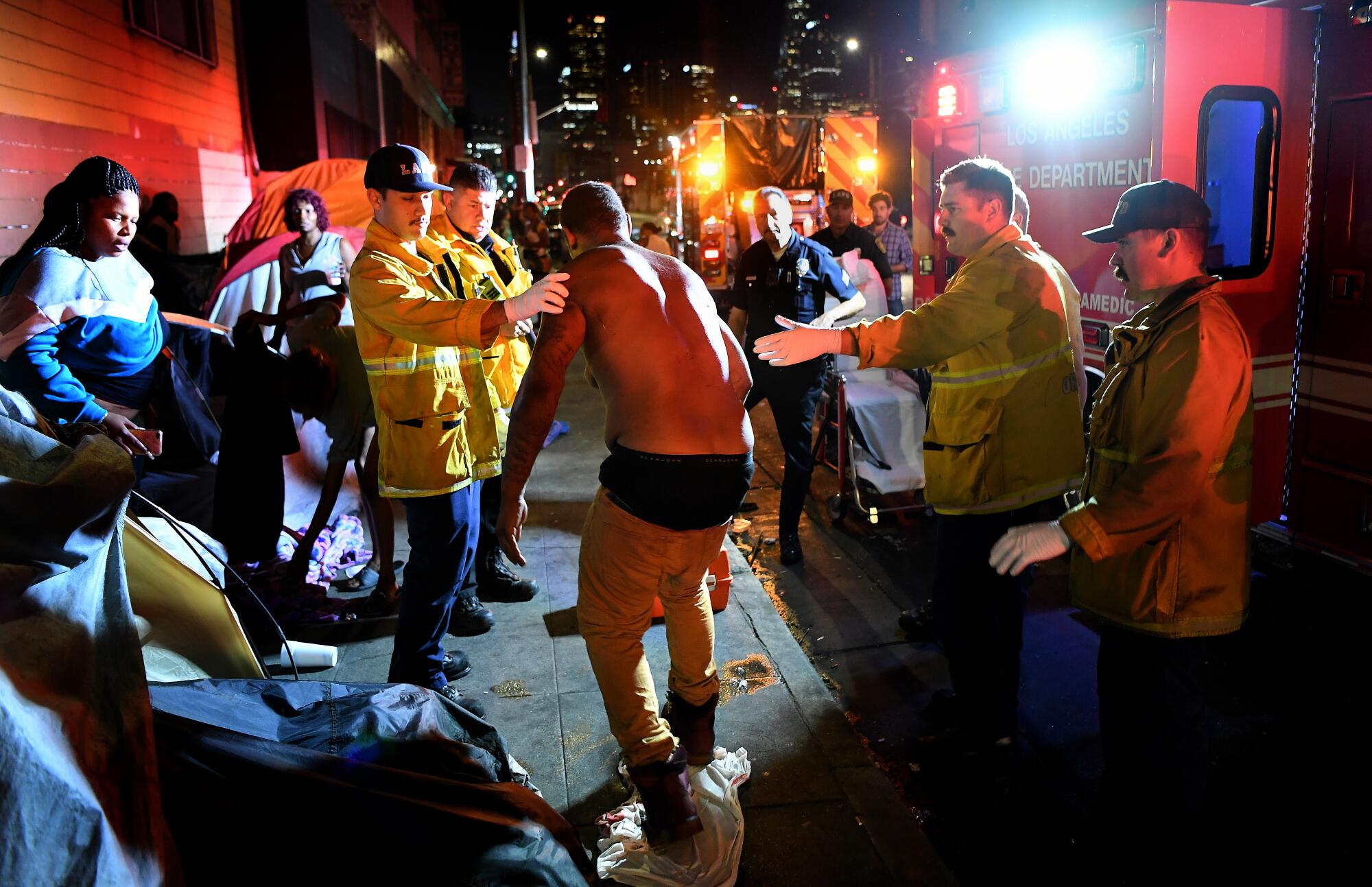 Firefighters help a stabbing victim to his feet in downtown Los Angeles