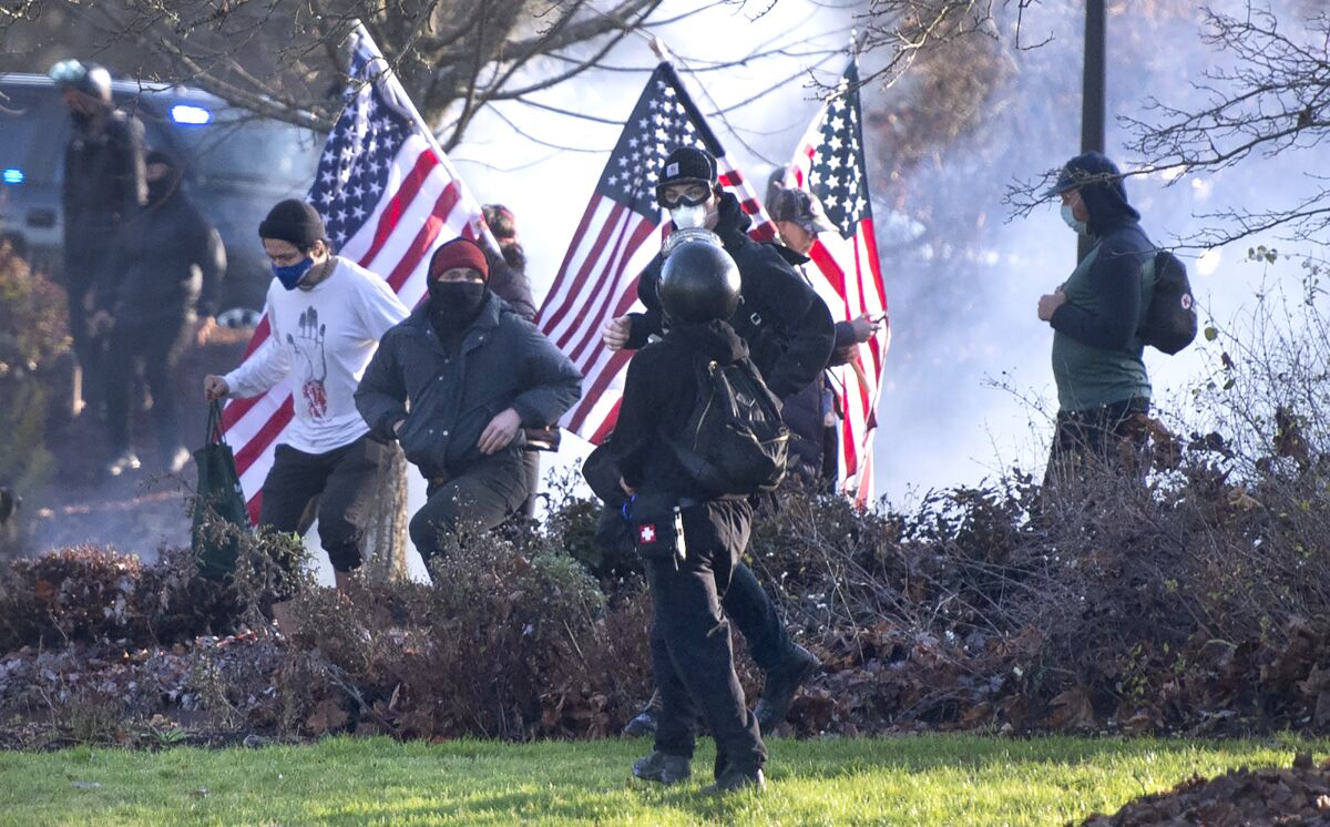 Supporters of President Donald Trump and antifa supporters clashed with Washington state police on the state Capitol Campus in Olympia, Wash., Saturday, Dec. 12, 2020. Police in Olympia declared a riot early Saturday afternoon and arrested at least one person as groups with different points of view held simultaneous protests. (The Olympian via AP)