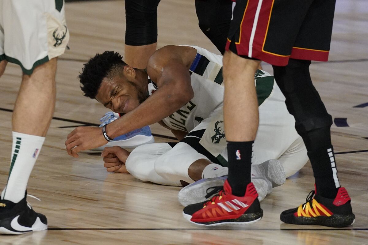 Milwaukee Bucks' Giannis Antetokounmpo (34) falls and injures his ankle slightly but continues to play in the first half of an NBA conference semifinal playoff basketball game against the Miami Heat Friday, Sept. 4, 2020, in Lake Buena Vista, Fla. (AP Photo/Mark J. Terrill)