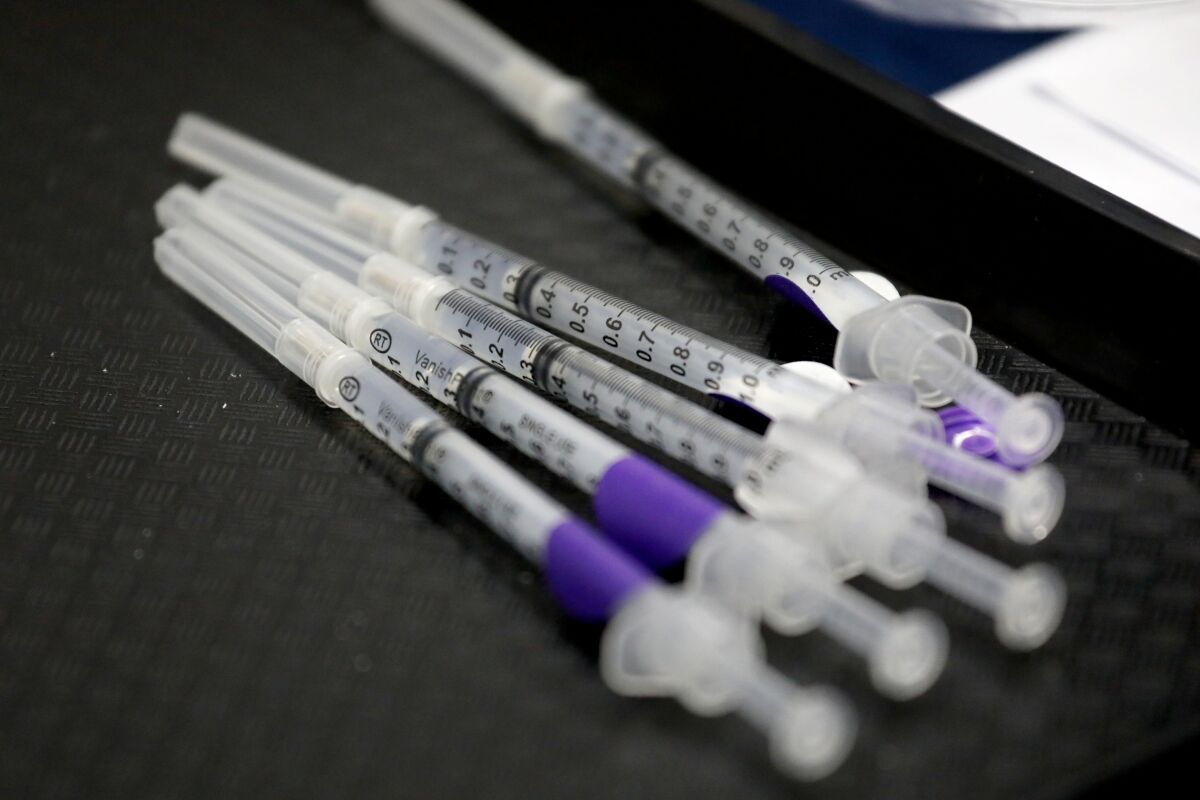 Five syringes, some with purple bands 