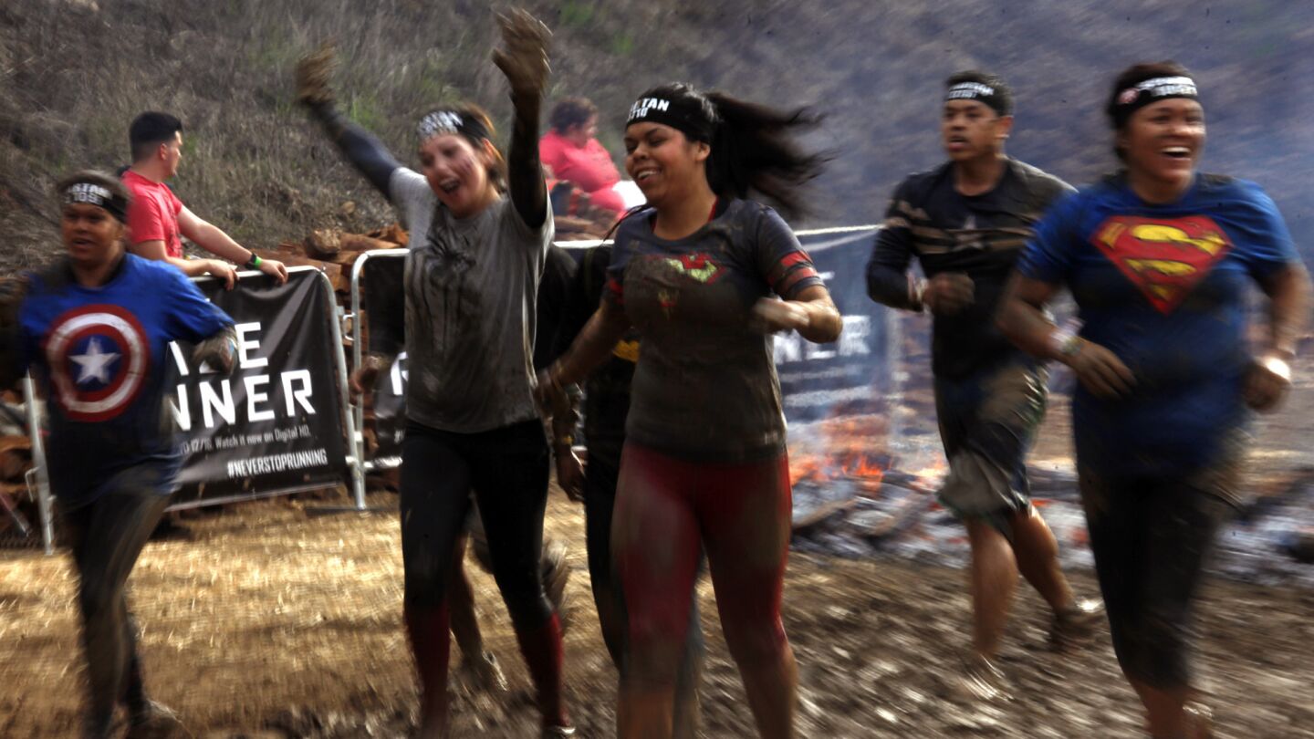 A muddy group of participants celebrate as they cross the finish line during the Spartan Race at Calamigos Ranch in Malibu on Dec. 7, 2014.