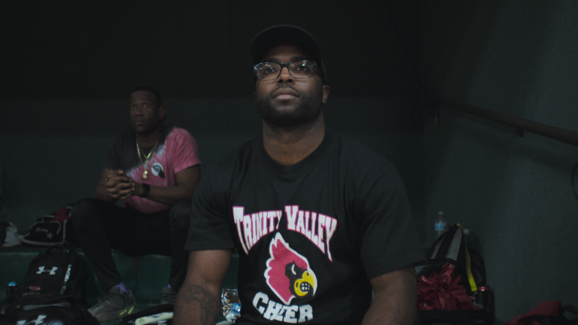 A man in glasses, cap and Trinity Valley Cheer T-shirt
