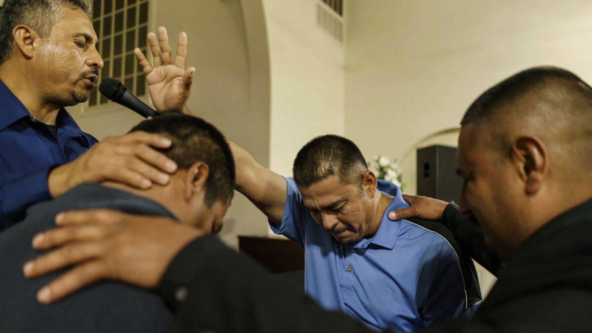 Pastor Guillermo Aceves, far left, and members of El Aposento Alto church in Wasco pray for his brother Jesus Aceves, third from left, who was detained by ICE agents during a raid Feb. 27.