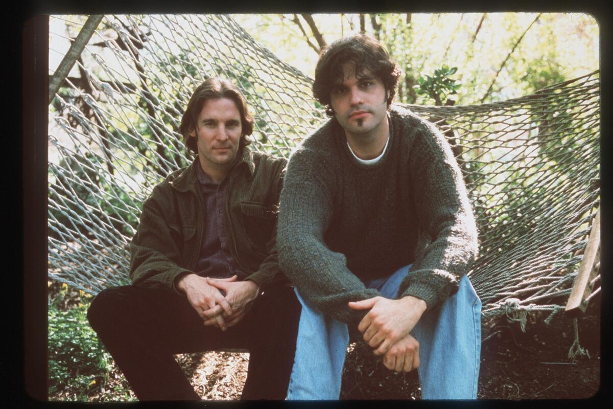 Two men sit in a hammock
